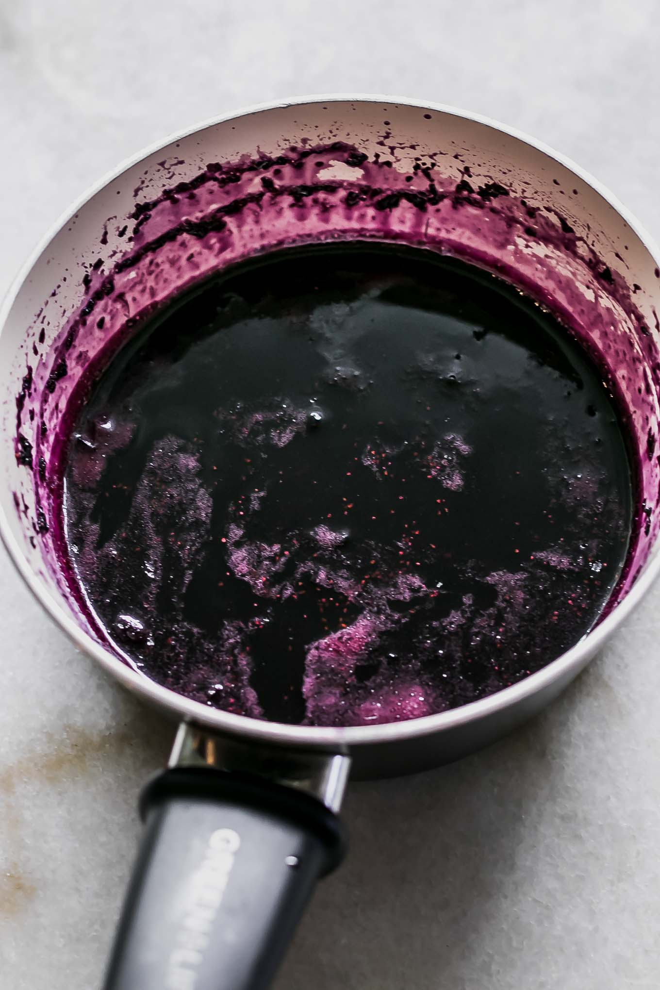 blueberry syrup in a white sauce pan on a white table