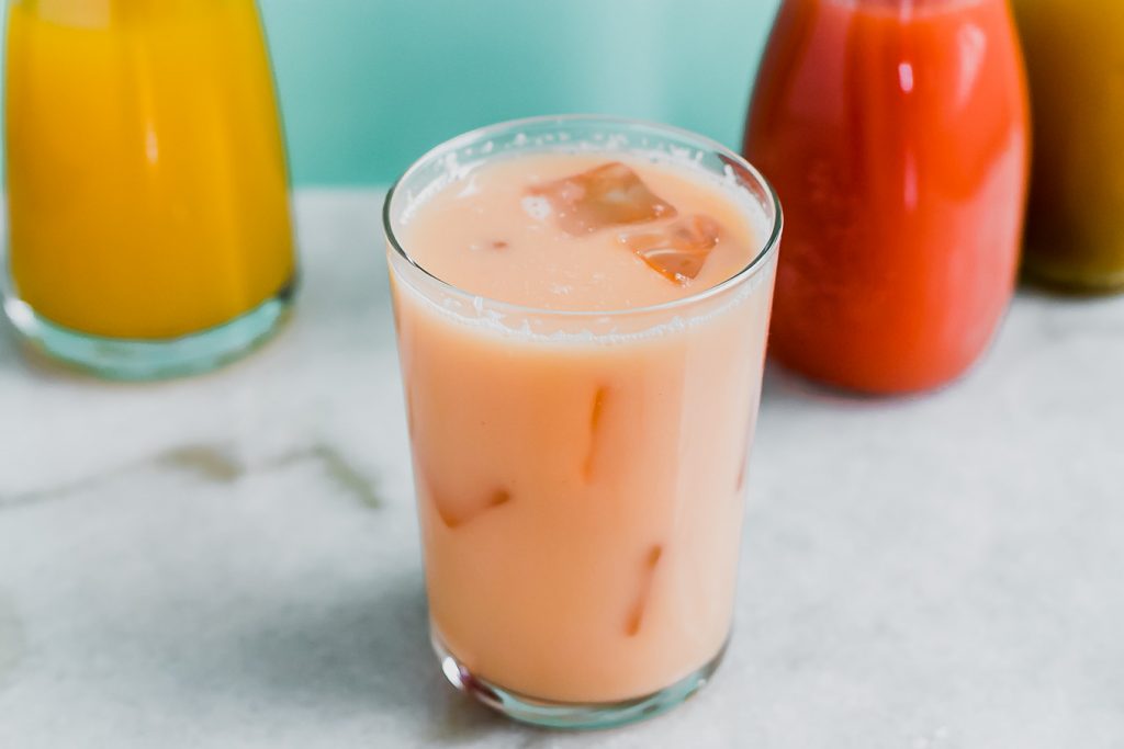 a pink coconut milk drink with guava and passionfruit juices on a white table