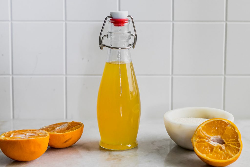 simple syrup with oranges on a white countertop