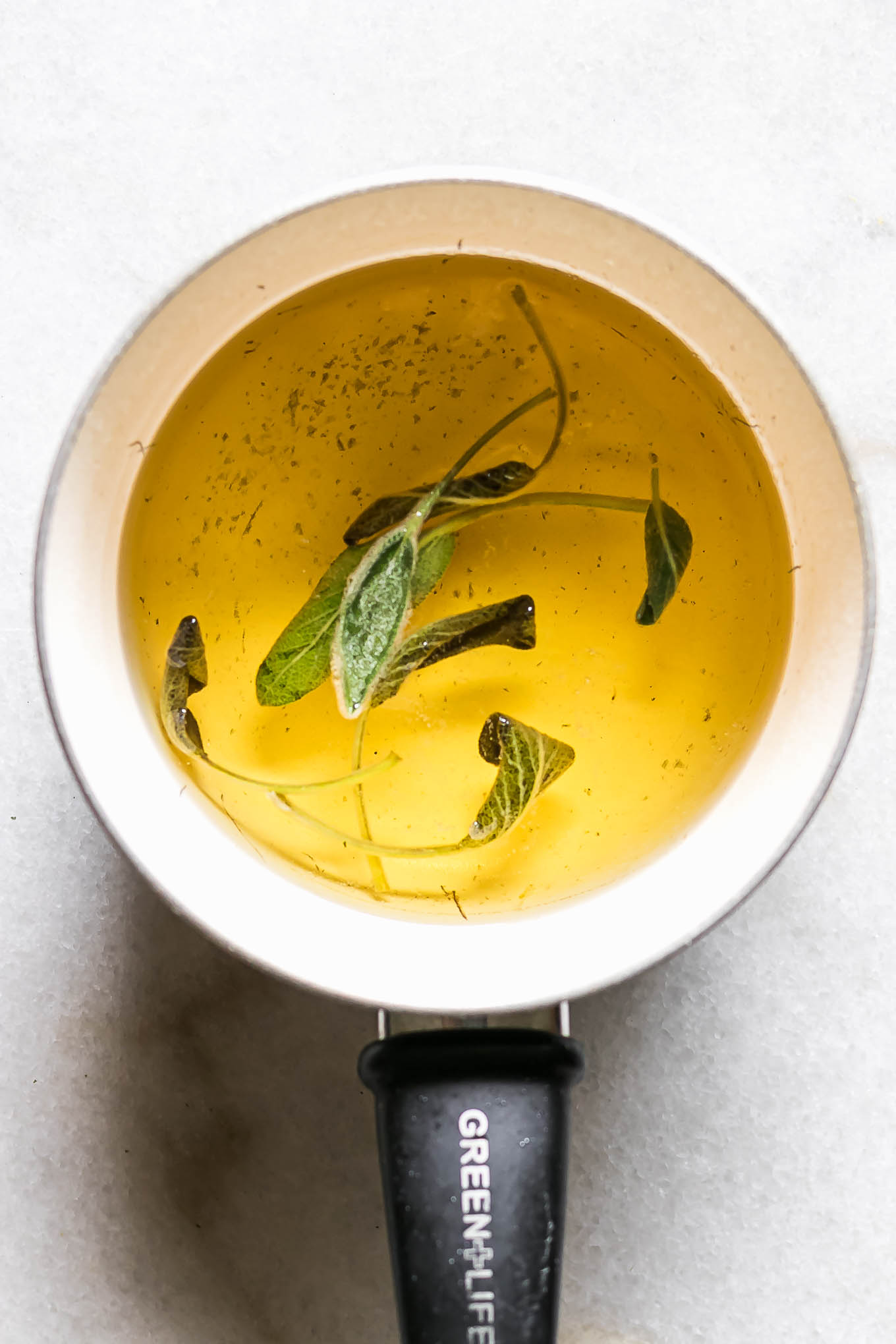 cooked sage simple syrup in a white saucepan