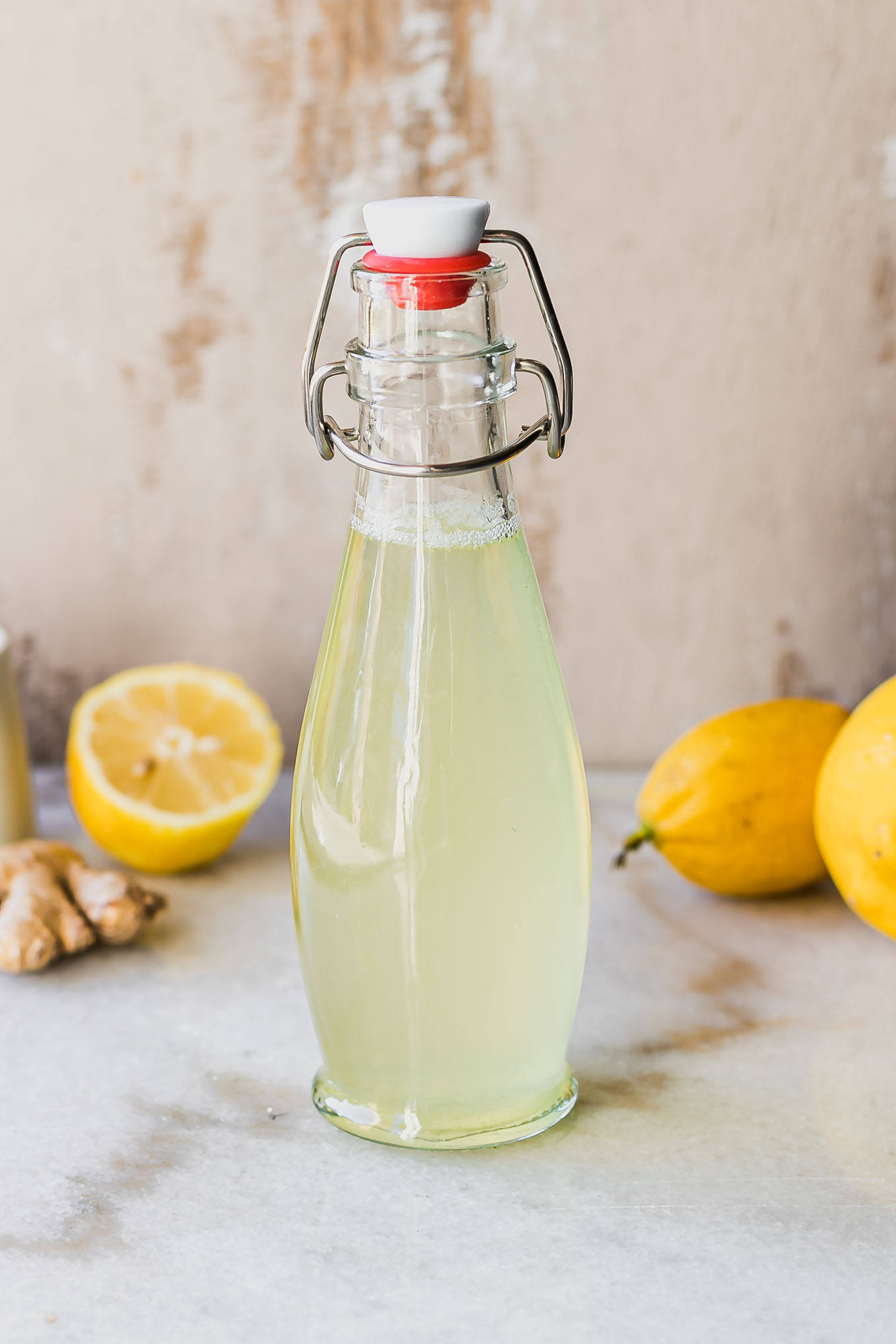 lemon and ginger infused simple syrup in a glass jar on a table with lemons and ginger