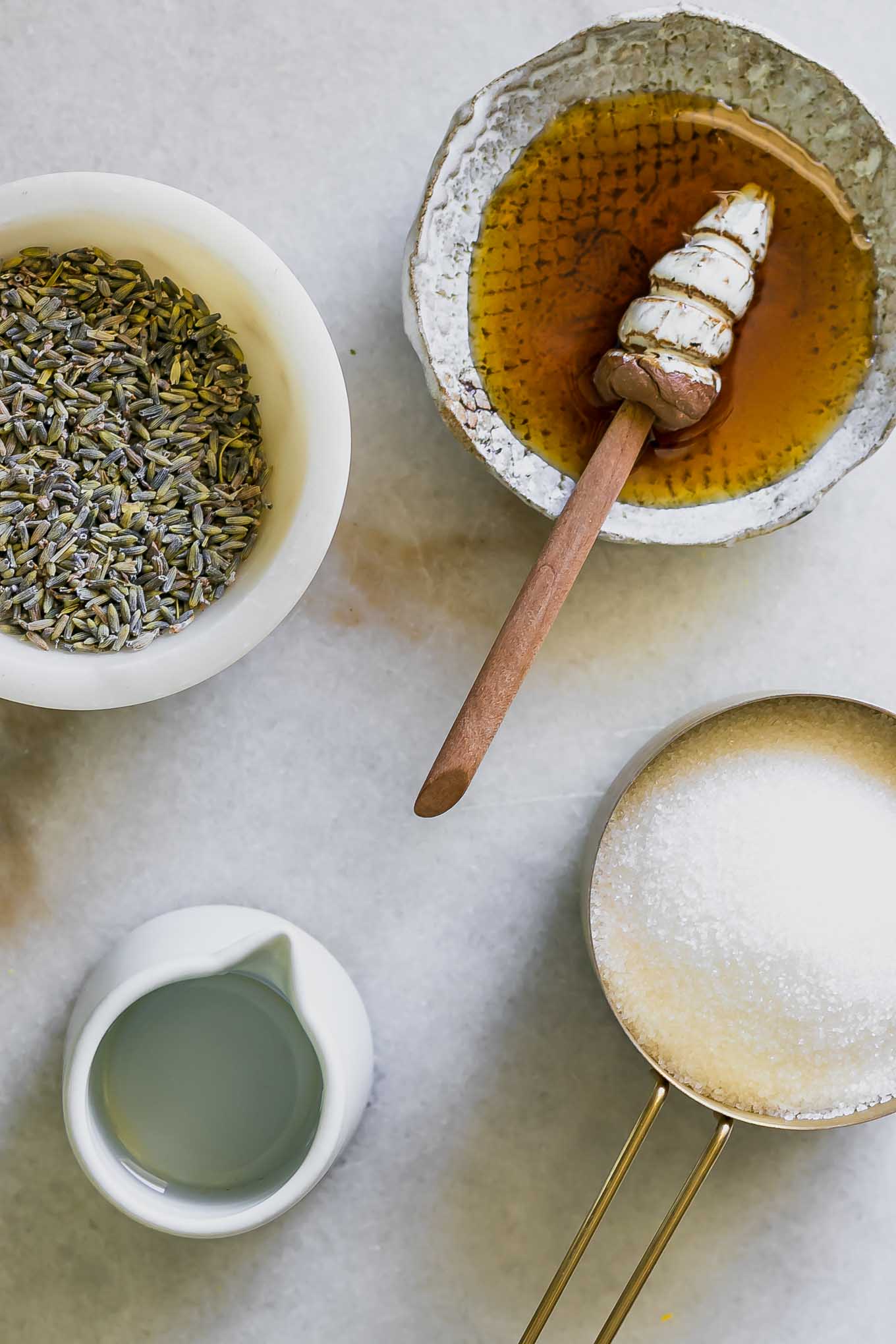 bowls of honey, dried lavender, sugar, and water on a white table