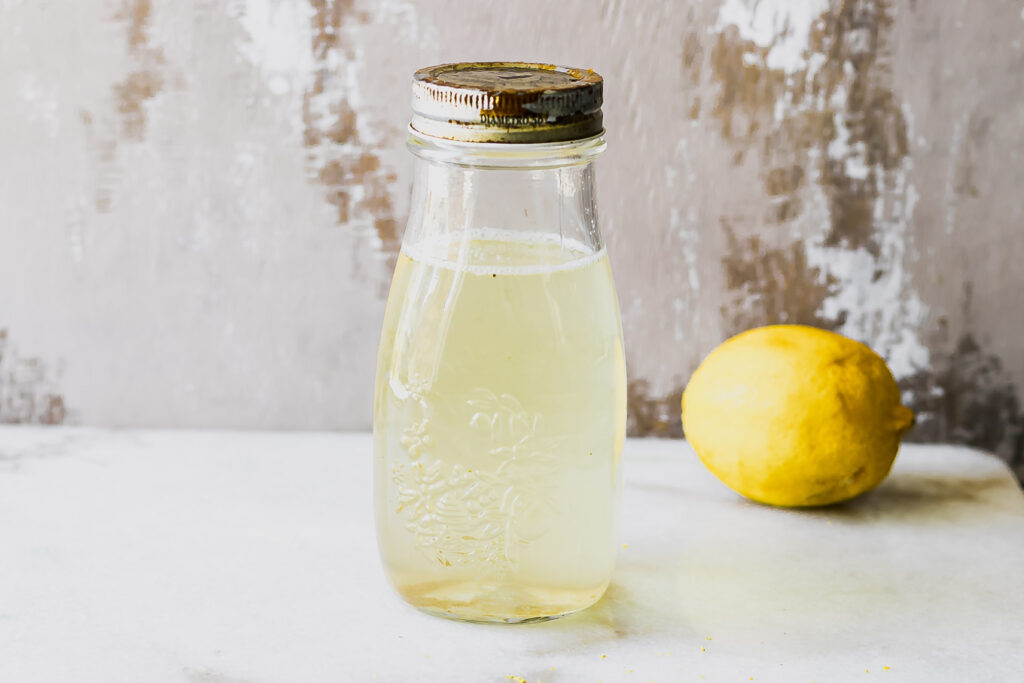 a jar of lemon cordial concentrate on a table with a lemon