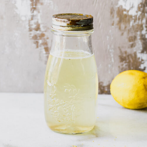 a jar of lemon cordial concentrate on a table with a lemon