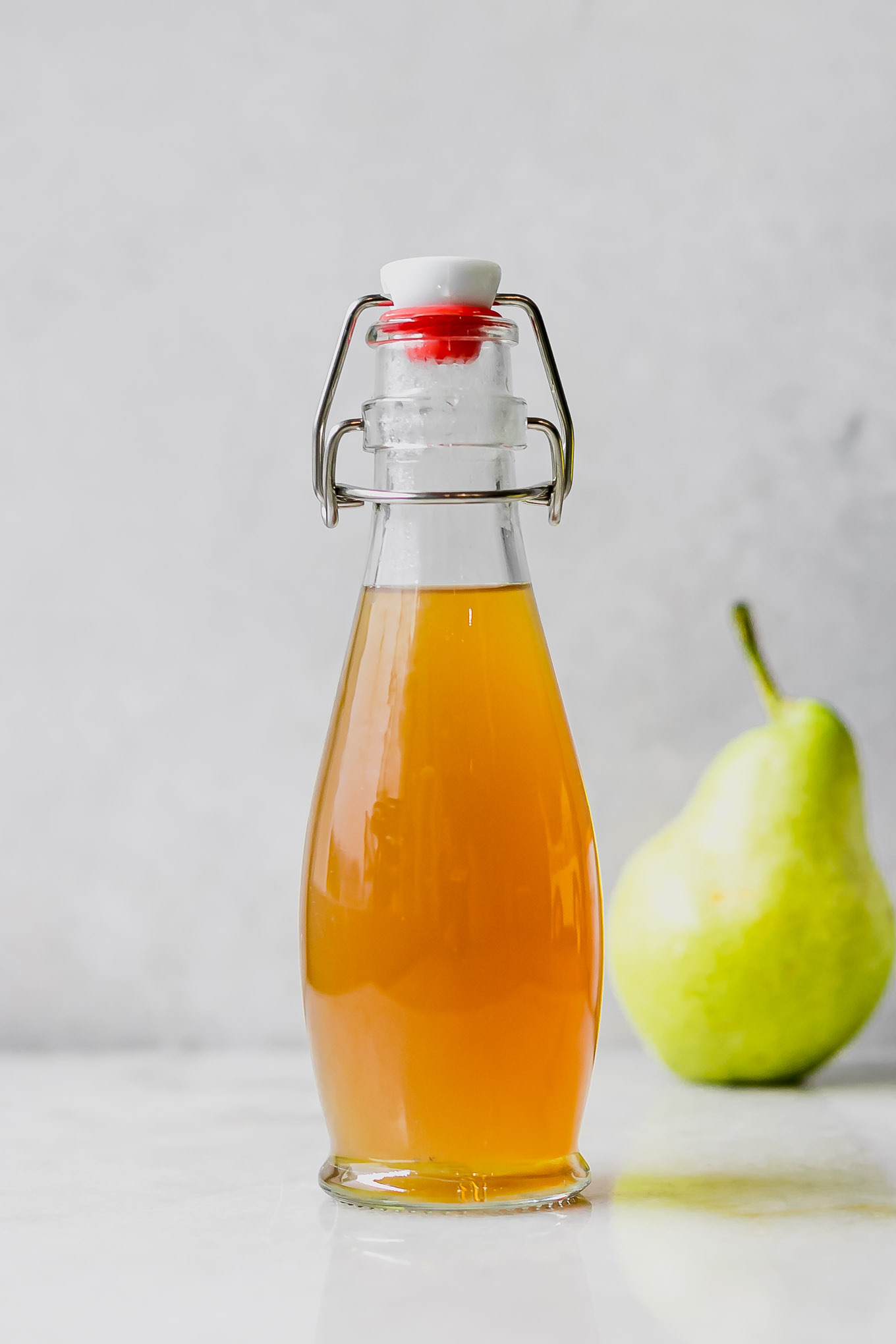 pear infused simple syrup in a glass bottle on a white countertop