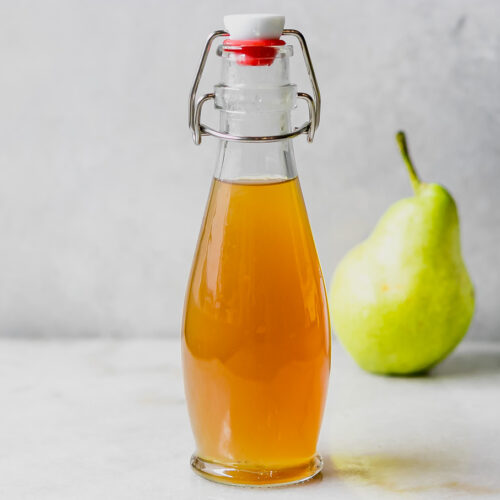 pear simple syrup in a glass jar on a table with a pear