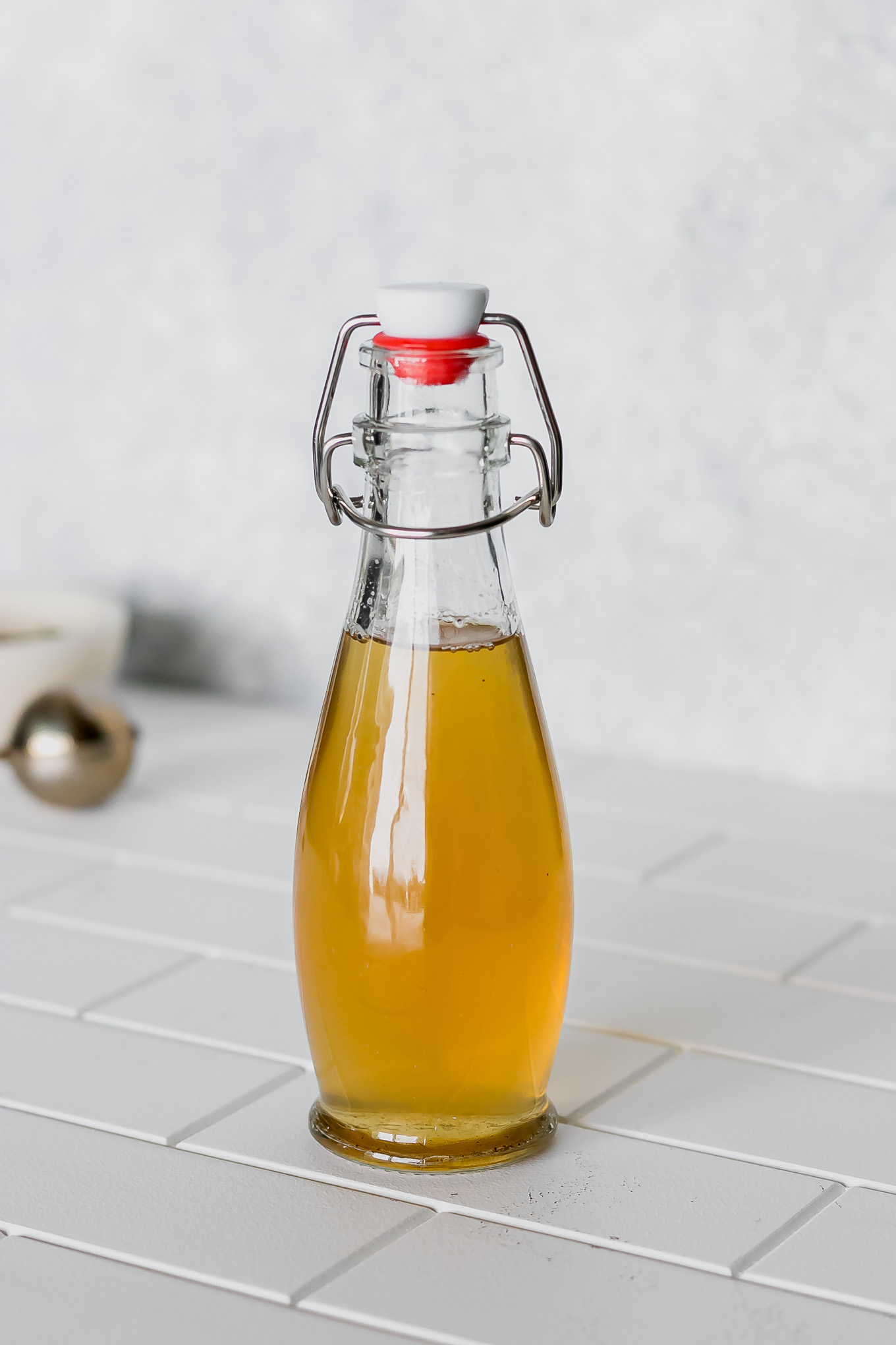 green tea infused simple syrup in a bottle on a white table