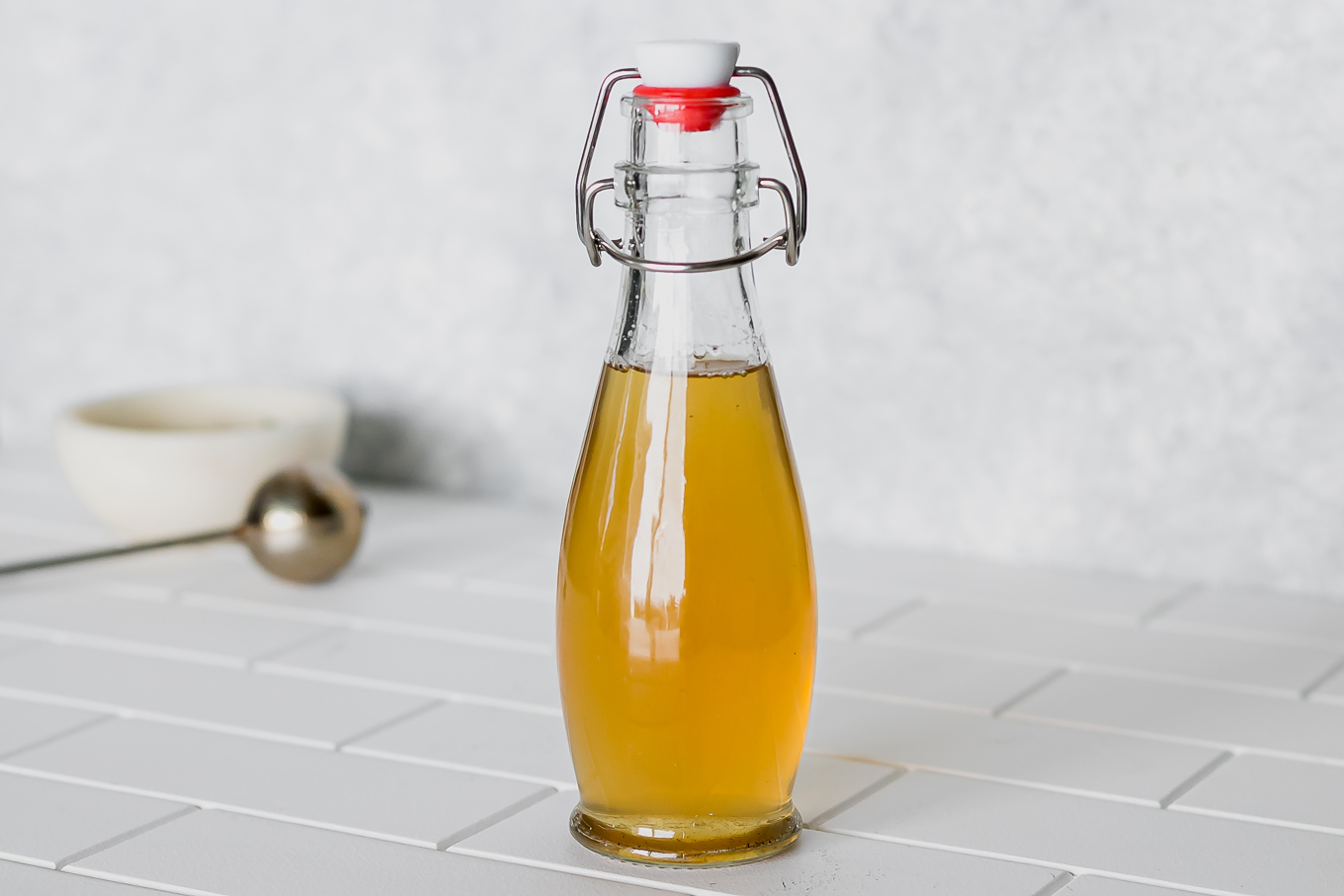 green tea simple syrup in a glass jar on a white countertop