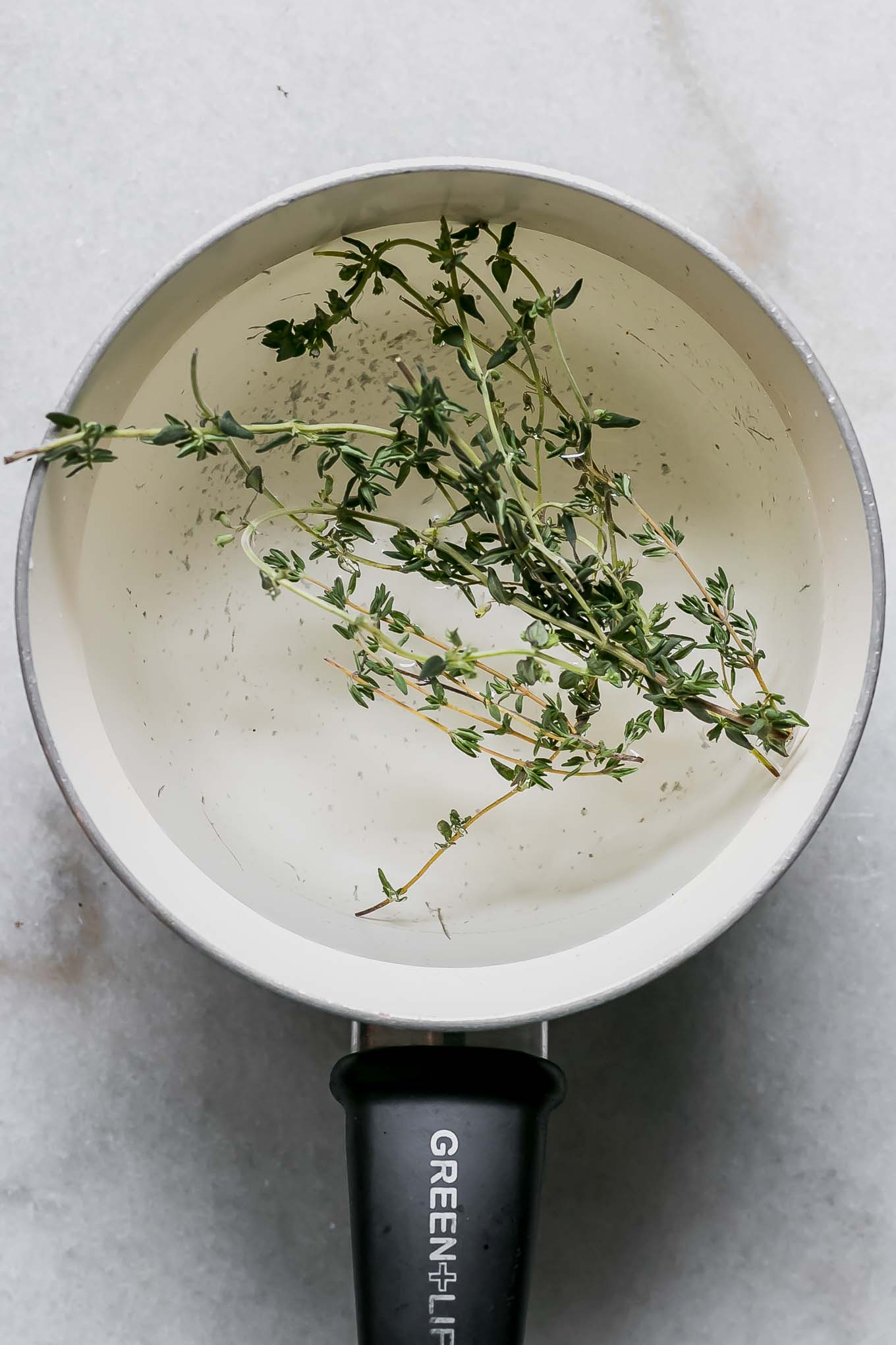 thyme leaves inside a pot with water and sugar for simple syrup