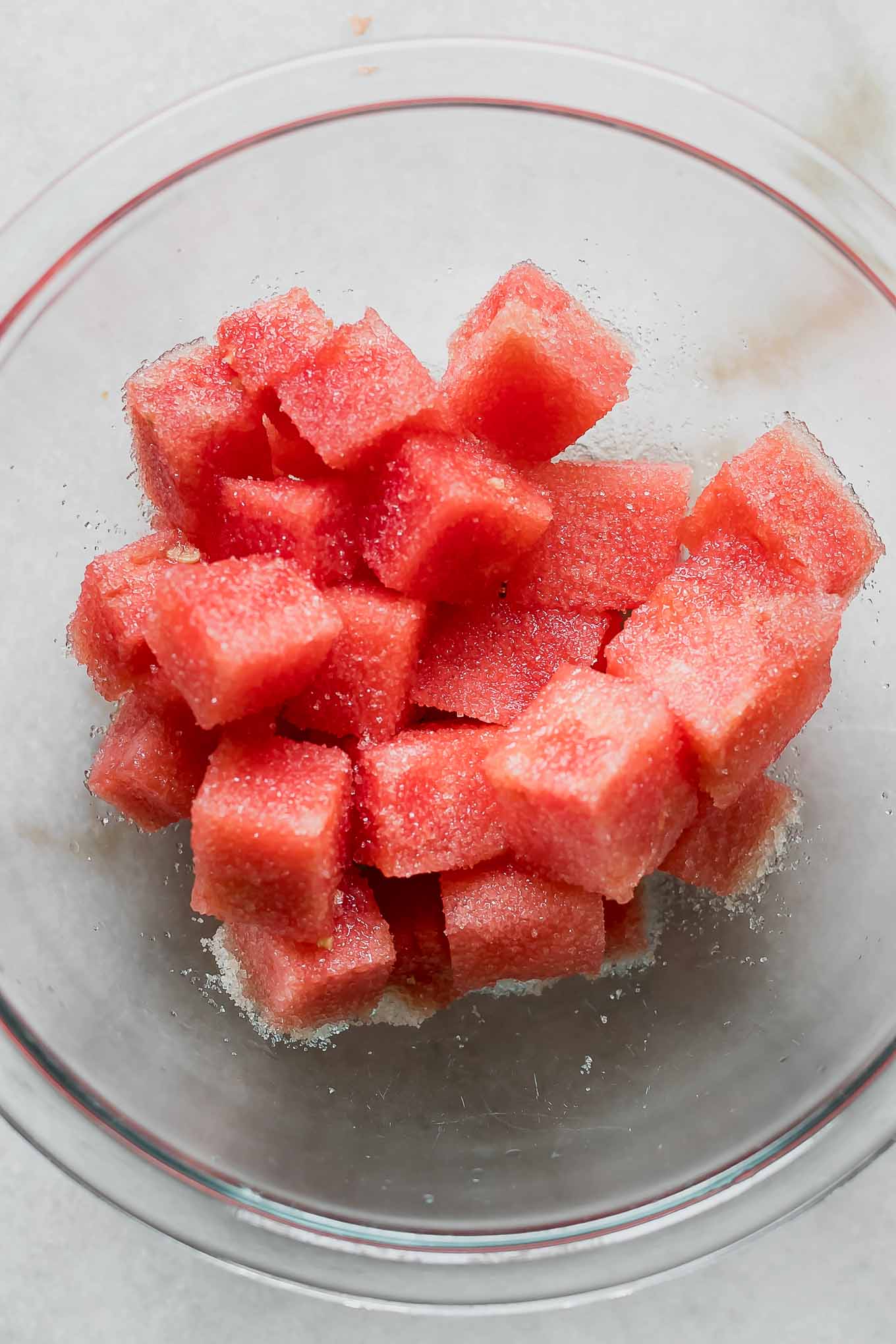cut watermelon with drizzled sugar in a glass bowl