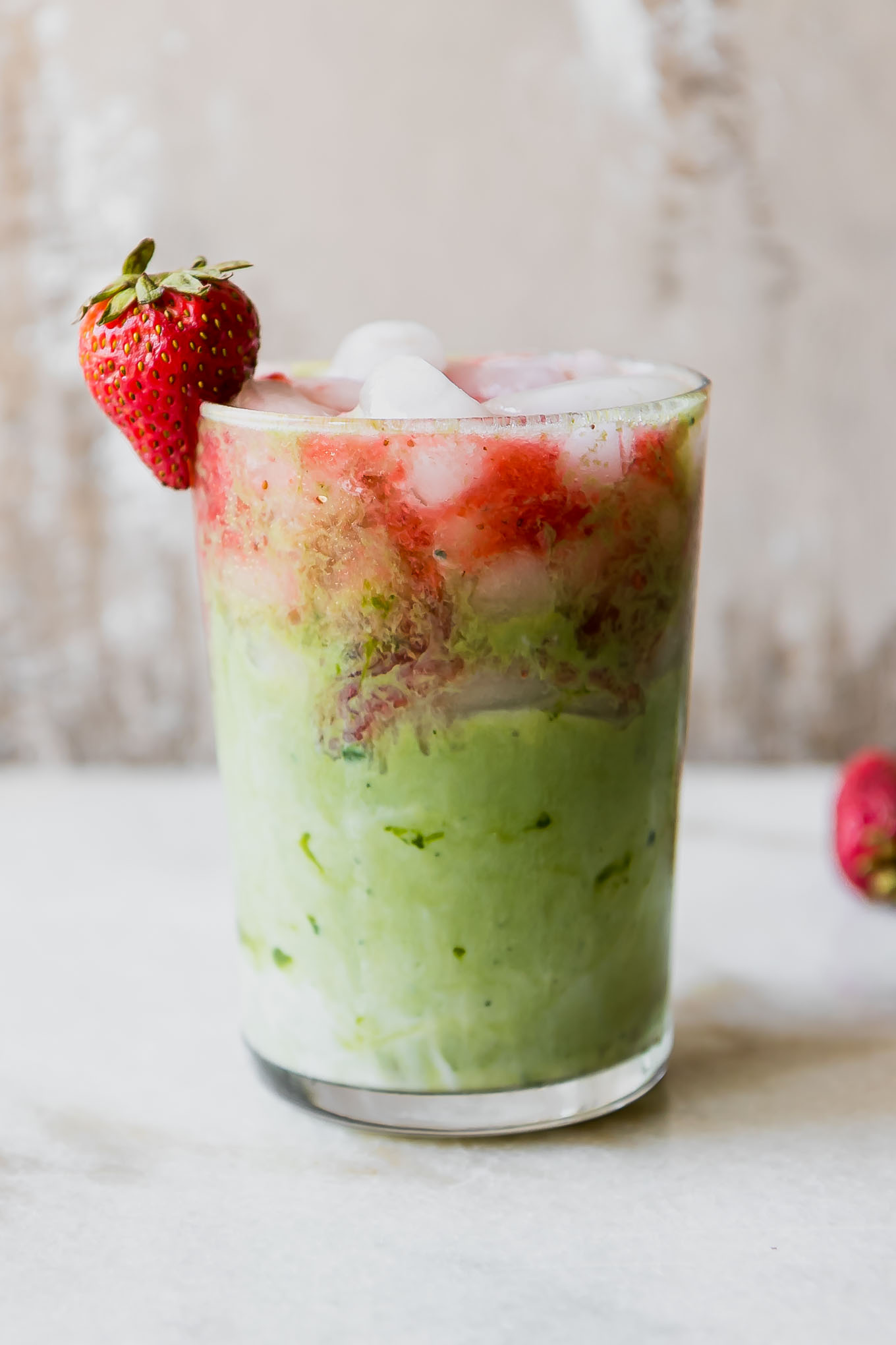 strawberry matcha latte in a glass with ice and a strawberry garnish