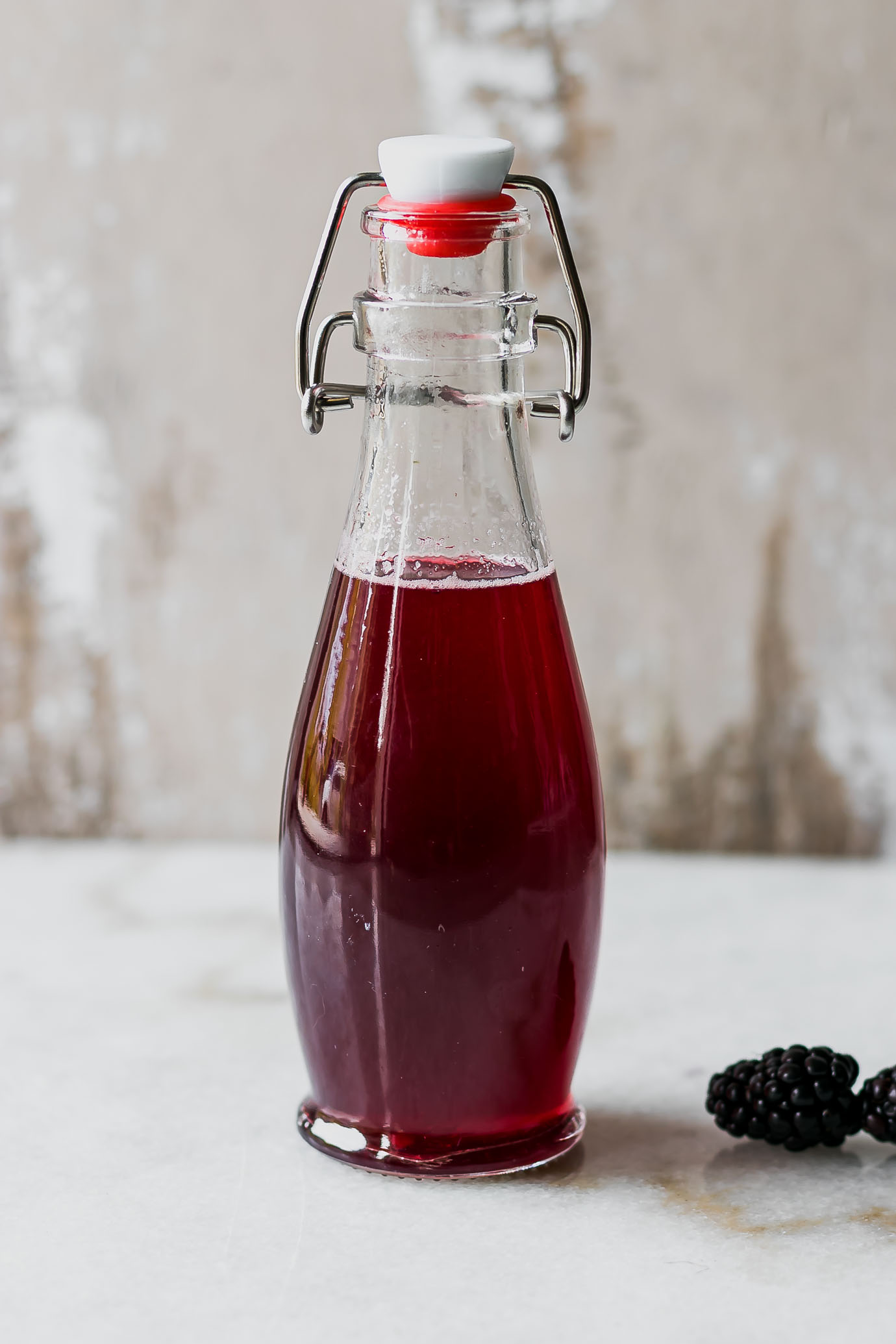 blackberry simple syrup in a jar on a white countertop