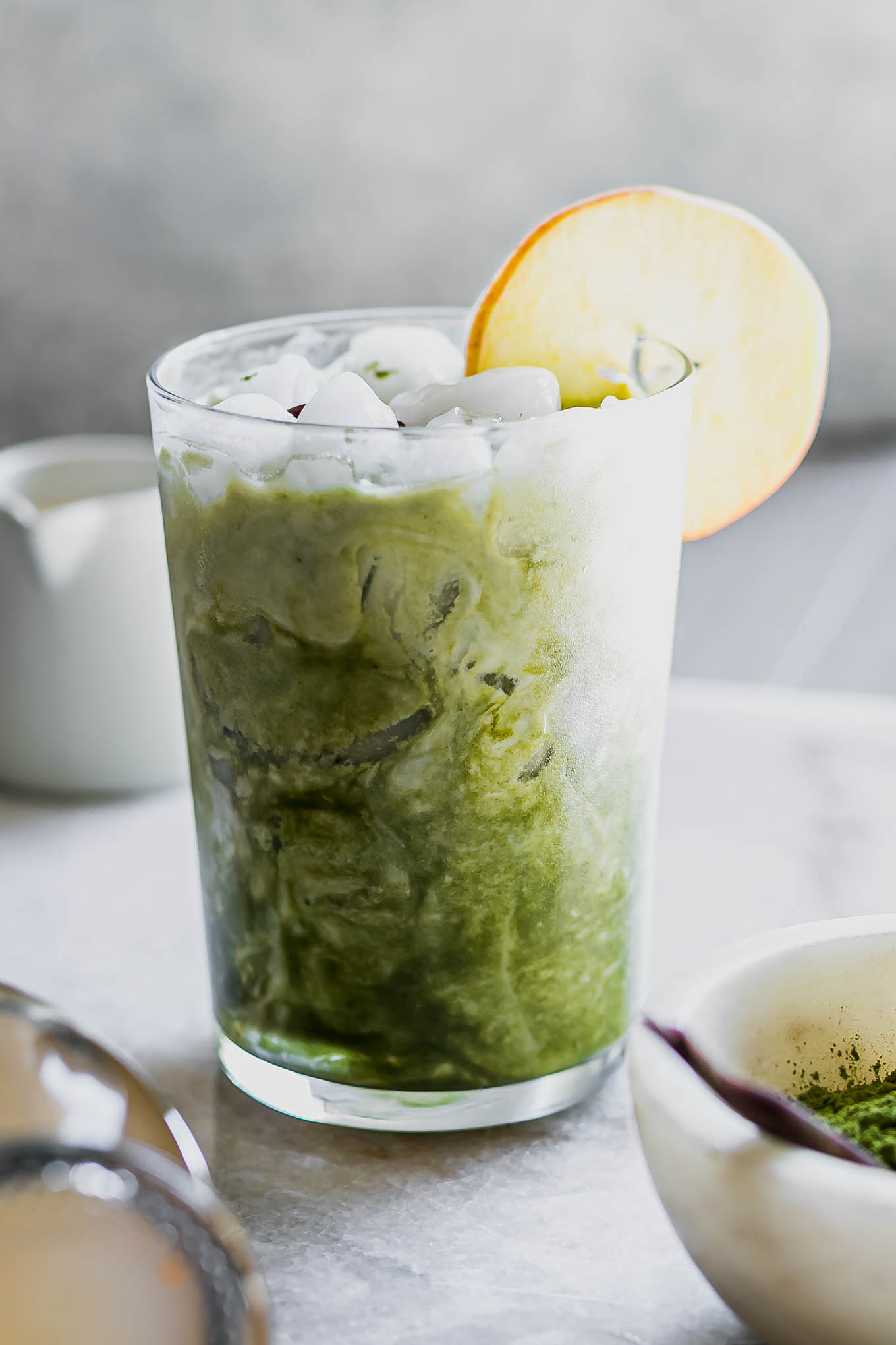 an apple matcha latte on a white table with an apple garnish