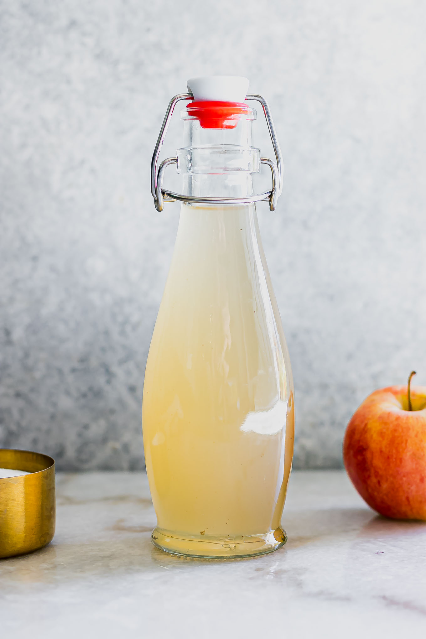 apple simple syrup in a glass jar on a white table